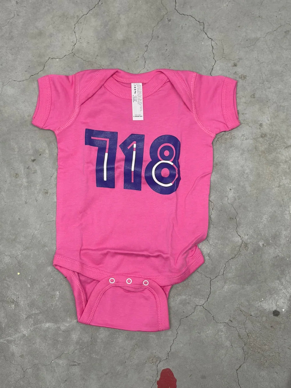 Pink baby onesie with purple '718' print