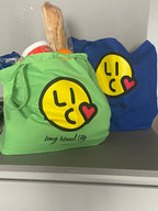 Green and blue tote bags with smiley face 'Long Island City' logo