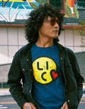 Person wearing a blue t-shirt with a yellow logo and black jacket outdoors.