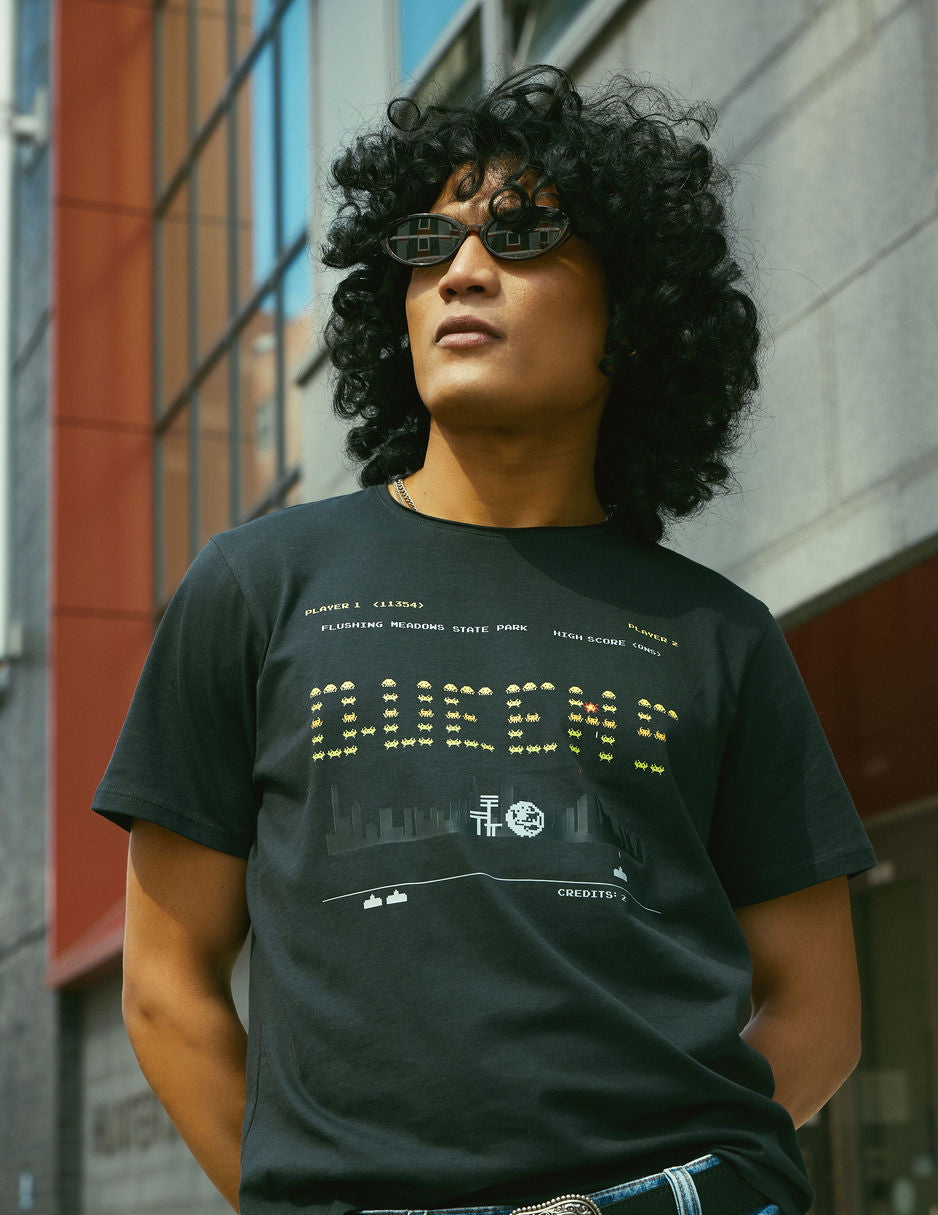 Person wearing a black t-shirt with text and graphics, standing outdoors.