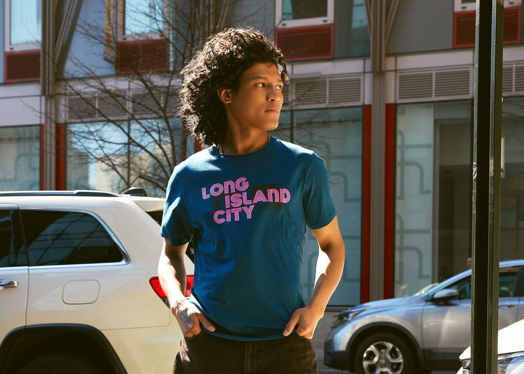 Person wearing a 'Long Island City' t-shirt standing outdoors with cars and buildings in the background