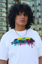 Person wearing a white t-shirt with colorful text design in an urban setting