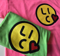 Green t-shirt with a smiley face design on a pink background