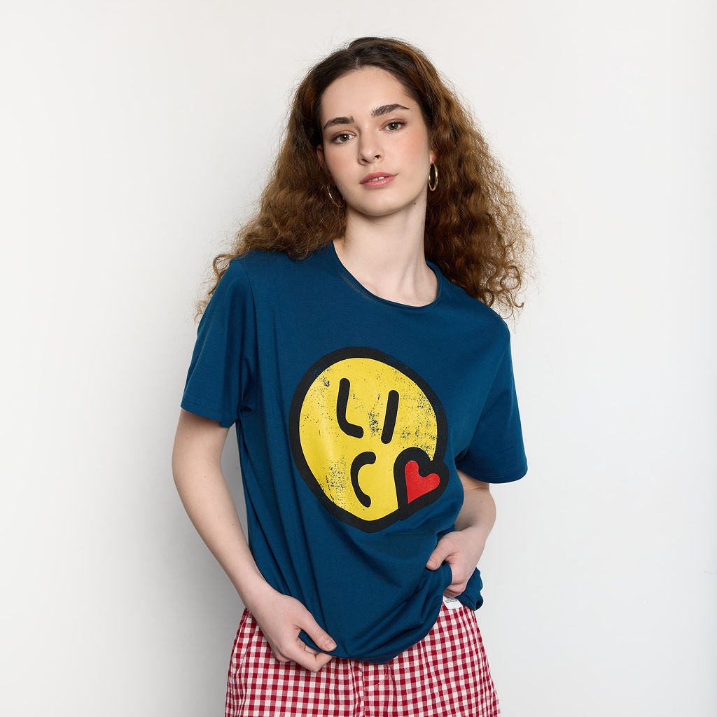 Woman wearing a blue t-shirt with a yellow smiley face design on a plain background