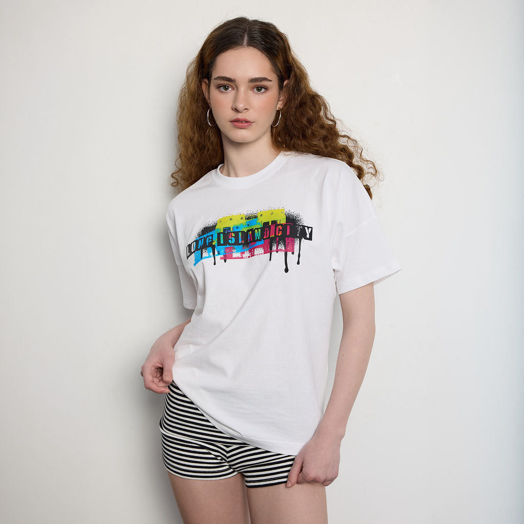 Woman wearing a white t-shirt with colorful text design on a plain background