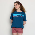 Woman wearing a blue t-shirt with a graphic design and red striped shorts against a white background