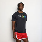 Person wearing a black t-shirt with colorful text and red shorts on a light gray background