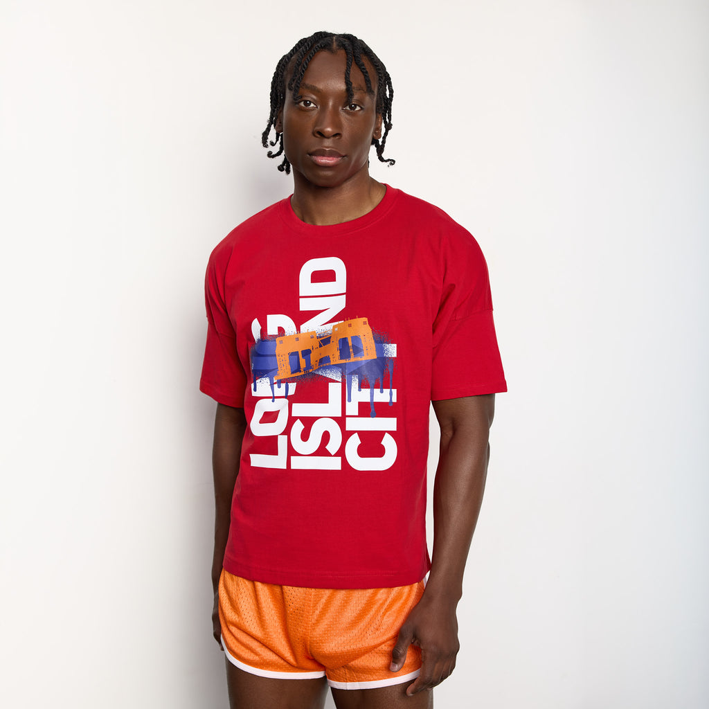 Person wearing a red t-shirt with graphic design and orange shorts on a white background