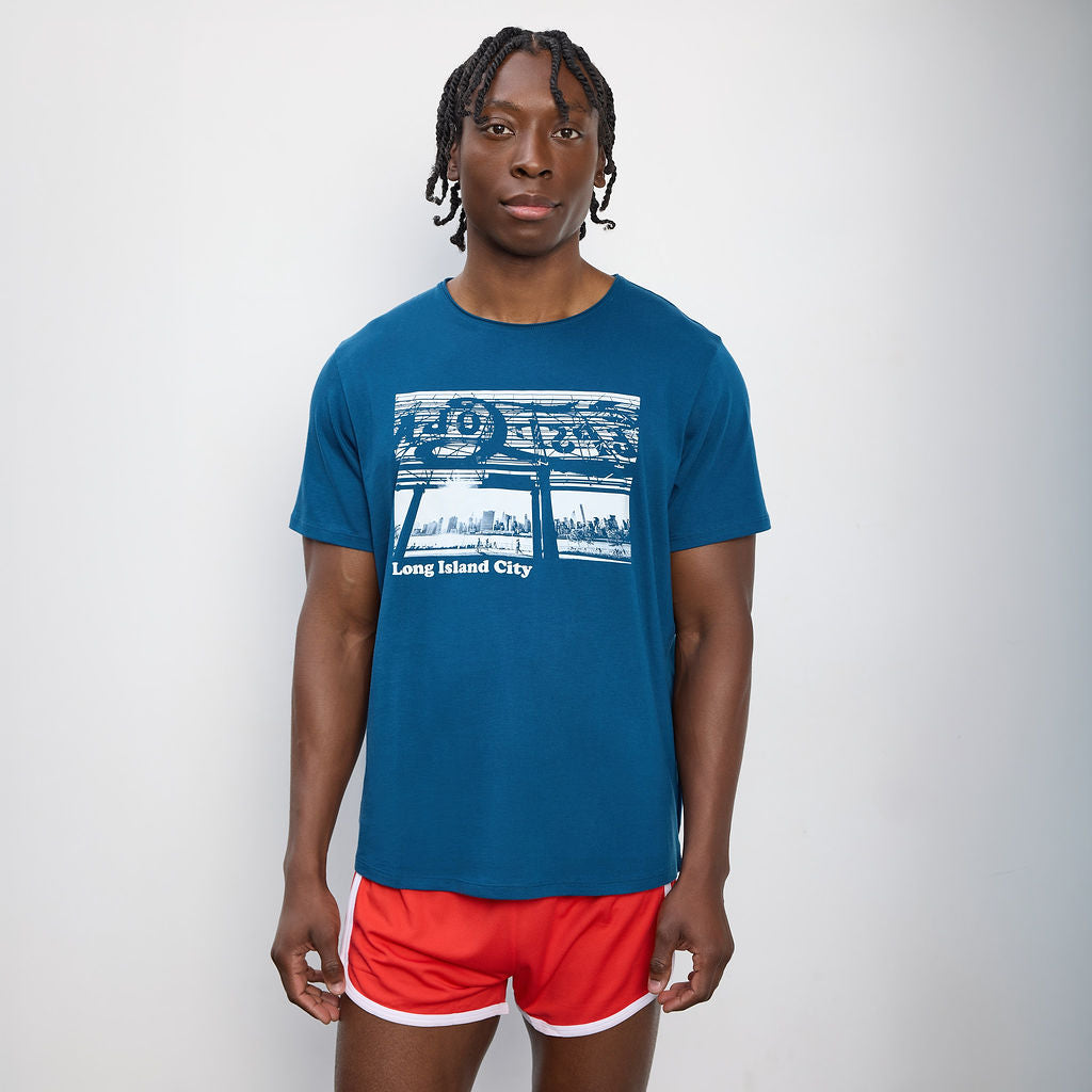 Person wearing a blue t-shirt with a graphic design and red shorts on a white background