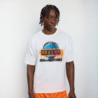 Person wearing a white t-shirt with 'Queens' graphic design on a plain background
